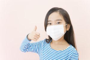 鼻風邪で乾燥予防のマスクをしている少女